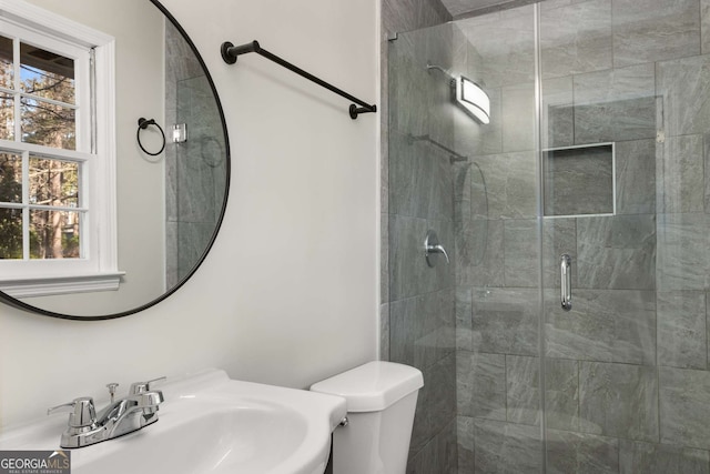 bathroom featuring a stall shower, plenty of natural light, a sink, and toilet