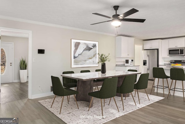 dining area with ornamental molding, light wood-type flooring, ceiling fan, and baseboards