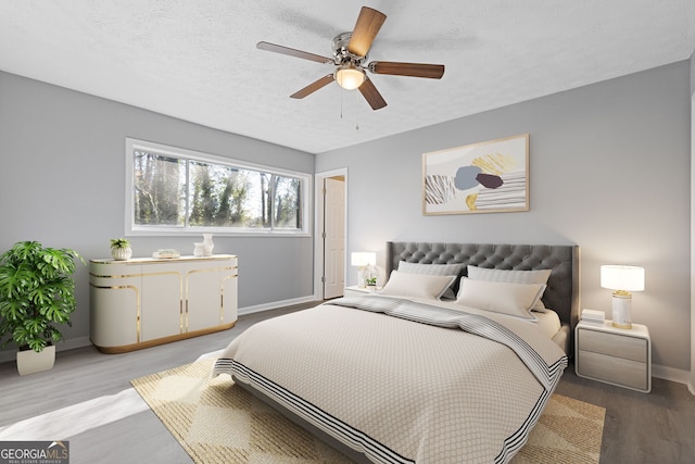 bedroom featuring a textured ceiling, wood finished floors, a ceiling fan, and baseboards