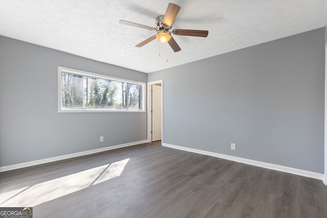 unfurnished room with a ceiling fan, dark wood-style flooring, a textured ceiling, and baseboards