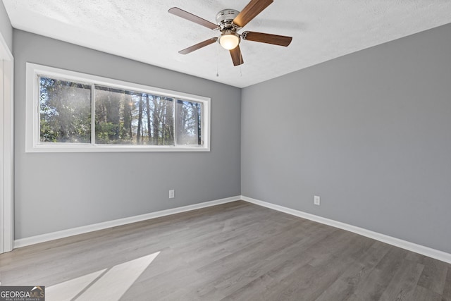 spare room with a ceiling fan, a textured ceiling, baseboards, and wood finished floors