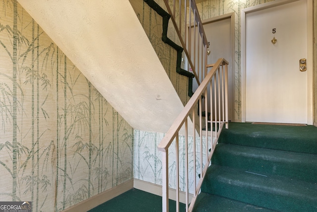 stairway featuring wallpapered walls and vaulted ceiling