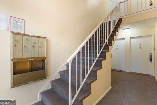 staircase featuring carpet, mail area, and baseboards