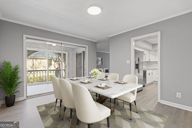 dining room featuring light wood-style floors, crown molding, and baseboards