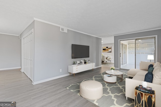 living room with baseboards, crown molding, visible vents, and wood finished floors