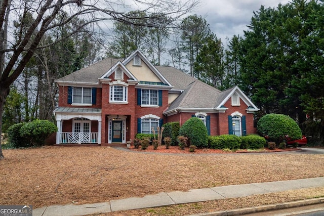 view of front of house with covered porch, roof with shingles, and brick siding