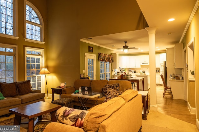 living room featuring light wood-style flooring, recessed lighting, a ceiling fan, decorative columns, and crown molding