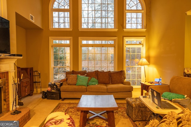 living room with a high ceiling, carpet, a fireplace, and visible vents