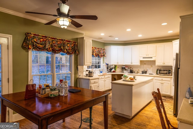 kitchen with light wood-style floors, a center island, stainless steel appliances, light countertops, and under cabinet range hood