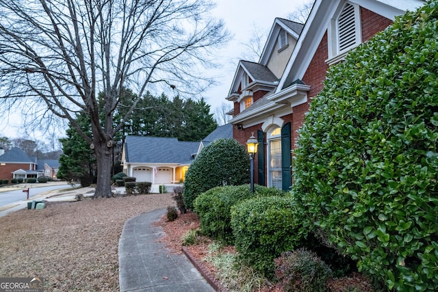 view of side of property featuring brick siding and an attached garage