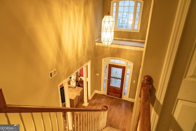 entrance foyer featuring a high ceiling, visible vents, baseboards, and wood finished floors