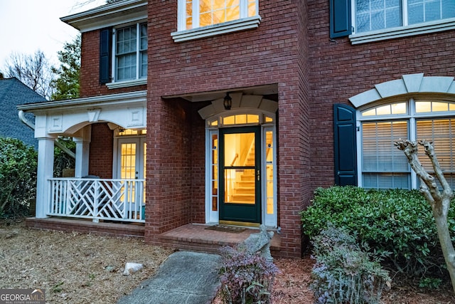 property entrance with covered porch and brick siding