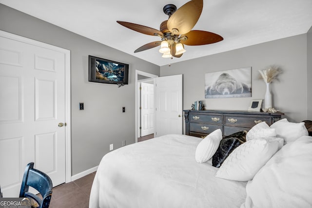 bedroom with dark tile patterned floors, baseboards, and a ceiling fan