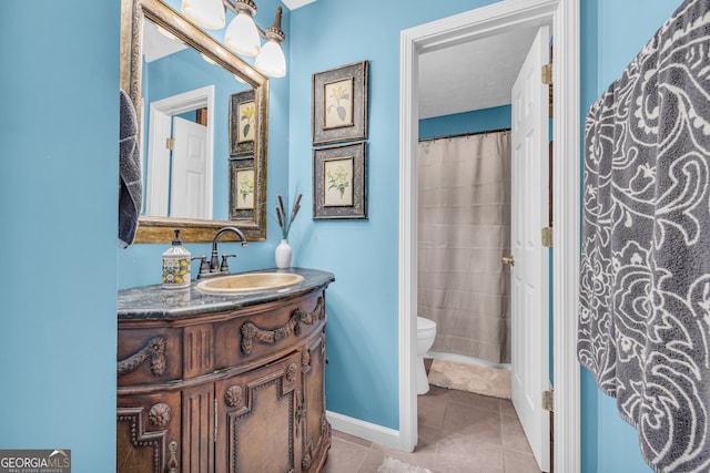 bathroom with tile patterned flooring, baseboards, vanity, and toilet