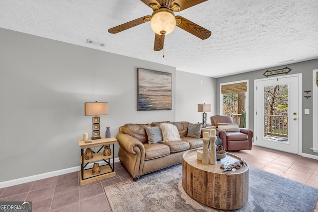 tiled living room with a textured ceiling, visible vents, and baseboards