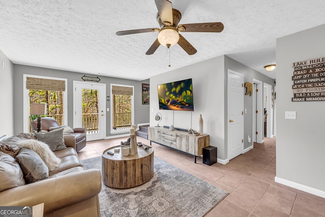 living area with a ceiling fan, a textured ceiling, baseboards, and light tile patterned floors