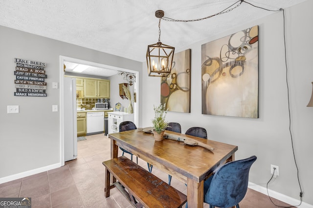 dining area with a textured ceiling, light tile patterned floors, baseboards, and an inviting chandelier