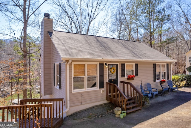 view of front of property with roof with shingles and a chimney