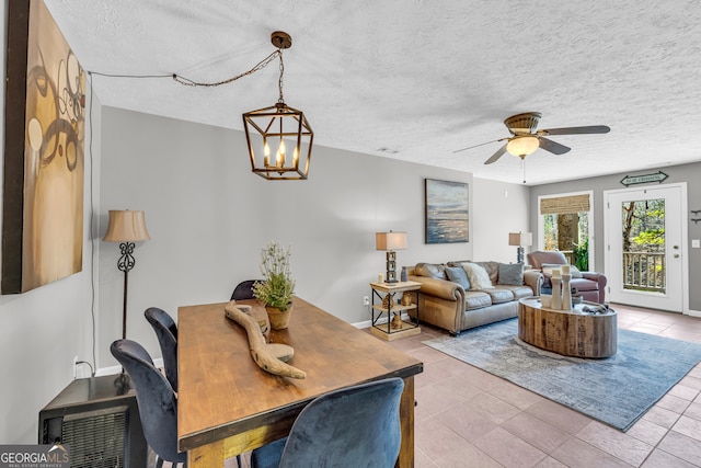 living room featuring a textured ceiling, light tile patterned floors, ceiling fan with notable chandelier, and baseboards