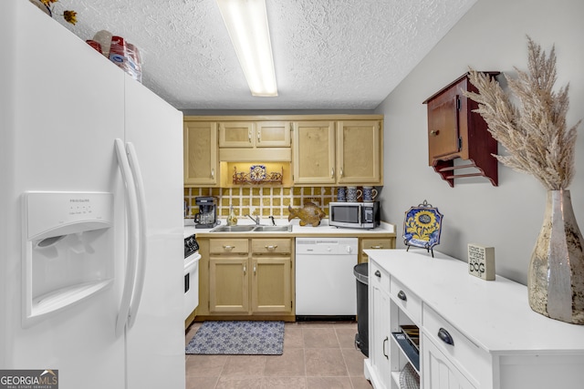 kitchen with light tile patterned floors, white appliances, a sink, light countertops, and decorative backsplash