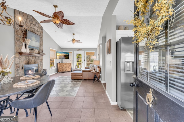 interior space with a fireplace, light tile patterned floors, ceiling fan, vaulted ceiling, and a textured ceiling