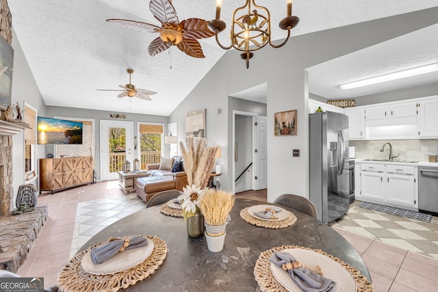 dining room with light tile patterned floors, vaulted ceiling, a textured ceiling, and ceiling fan with notable chandelier