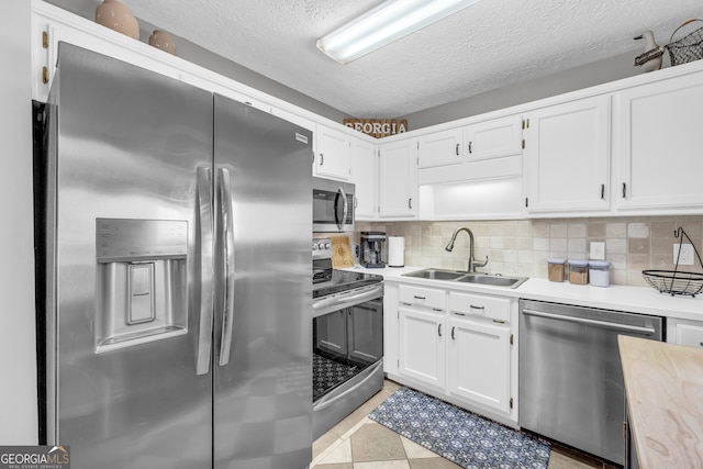 kitchen featuring white cabinets, appliances with stainless steel finishes, light countertops, and a sink