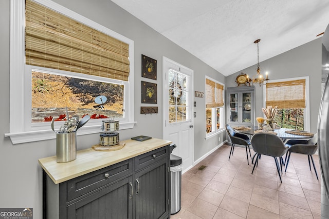 dining area featuring a chandelier, lofted ceiling, plenty of natural light, and light tile patterned floors