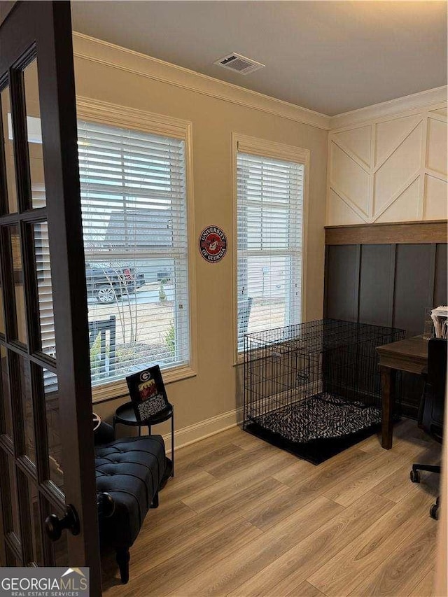 interior space with visible vents, crown molding, light wood-style flooring, and multiple windows