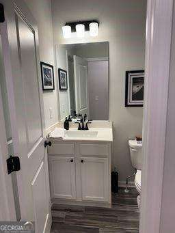 bathroom with vanity, wood finished floors, and toilet