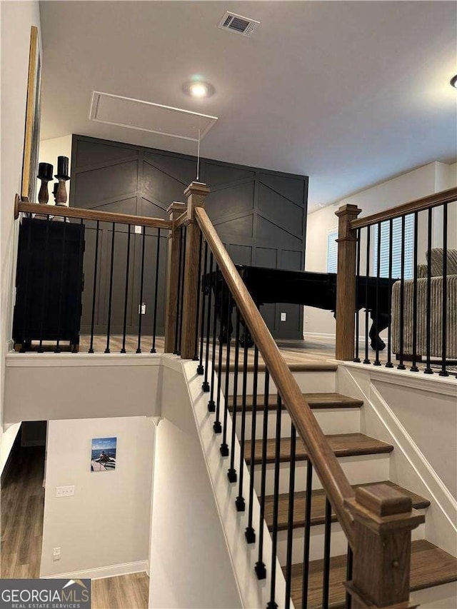 staircase featuring attic access, visible vents, and wood finished floors