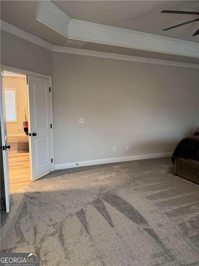 unfurnished bedroom with baseboards, carpet, a tray ceiling, and crown molding