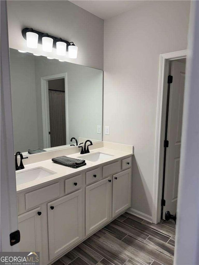 bathroom with double vanity, a sink, and wood finish floors