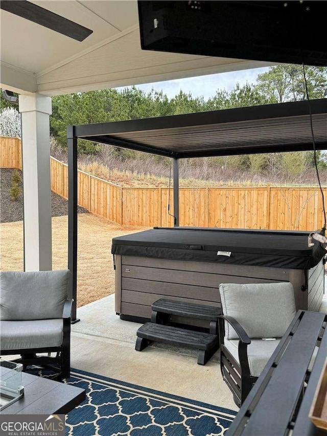 view of patio / terrace featuring a hot tub and fence