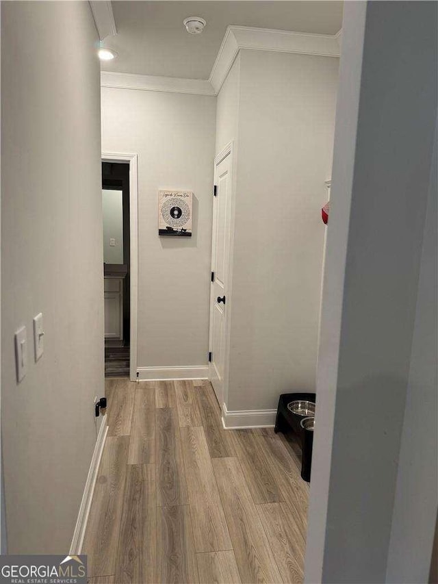 hall featuring ornamental molding, baseboards, and wood finished floors