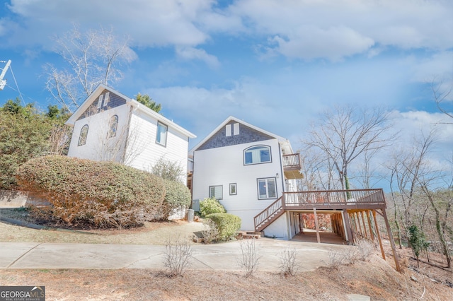 view of front of property with an attached carport, driveway, a wooden deck, and stairs