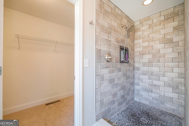 full bathroom featuring visible vents, a tile shower, a spacious closet, and baseboards