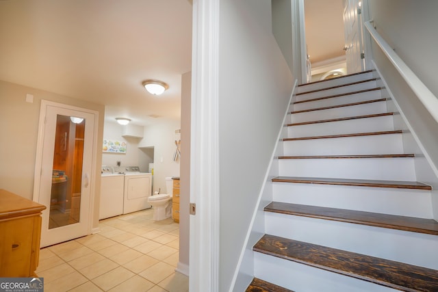 stairway with tile patterned flooring and separate washer and dryer