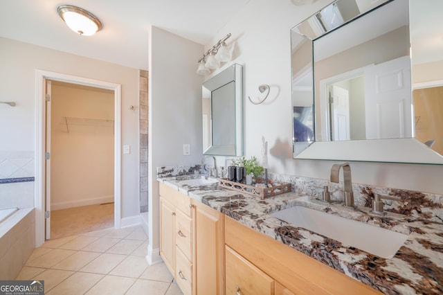 bathroom featuring a walk in closet, double vanity, a sink, and tile patterned floors