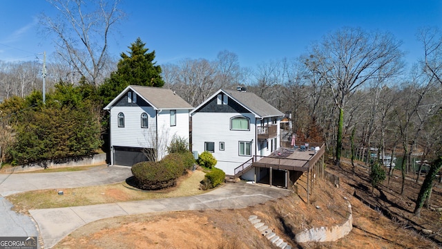 view of side of home with a balcony, an attached garage, stairway, and concrete driveway