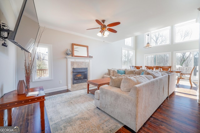 living room with a healthy amount of sunlight, ornamental molding, dark wood finished floors, and a tile fireplace