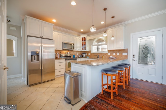 kitchen with stainless steel appliances, a peninsula, white cabinets, tasteful backsplash, and crown molding