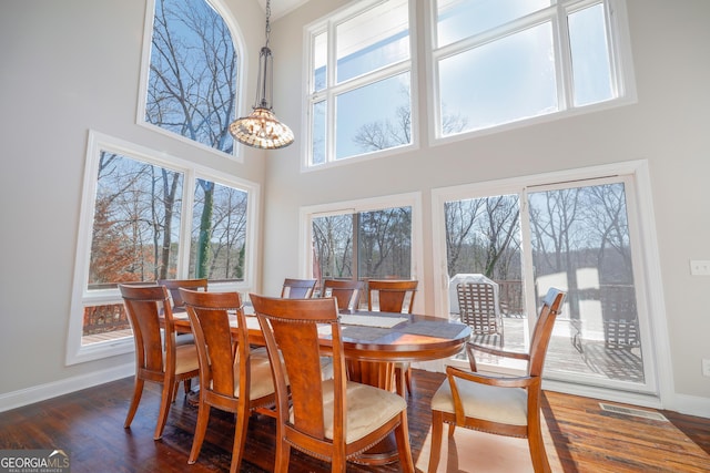 dining room featuring a high ceiling, visible vents, baseboards, dark wood finished floors, and an inviting chandelier