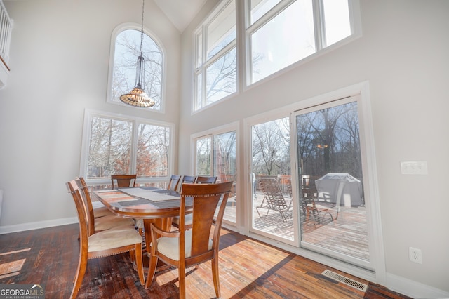 dining room featuring high vaulted ceiling, baseboards, visible vents, and hardwood / wood-style floors