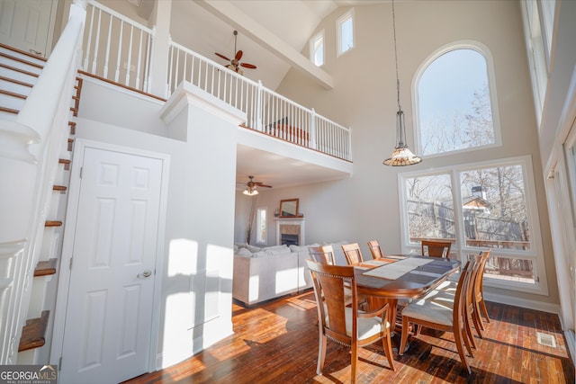 dining area with visible vents, a tiled fireplace, dark wood-style floors, ceiling fan, and stairway