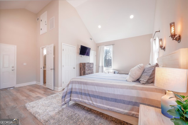 bedroom with high vaulted ceiling, recessed lighting, wood finished floors, visible vents, and baseboards