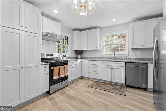 kitchen featuring light stone counters, light wood finished floors, appliances with stainless steel finishes, white cabinetry, and under cabinet range hood