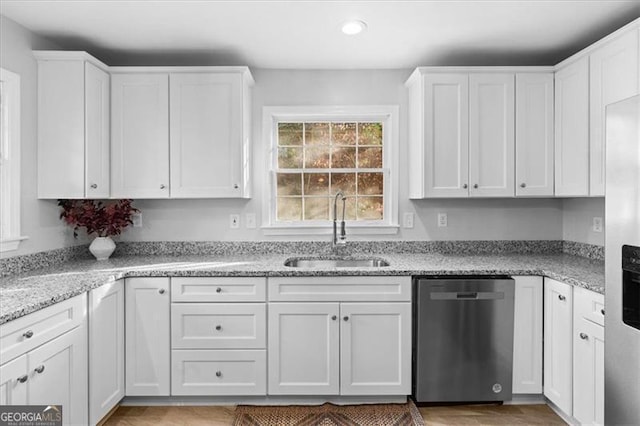 kitchen with dishwasher, light stone counters, a sink, and white cabinetry