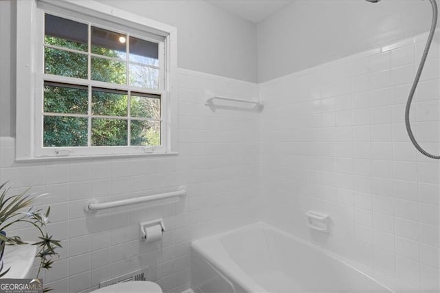 bathroom featuring toilet, tile walls, and shower / bathing tub combination