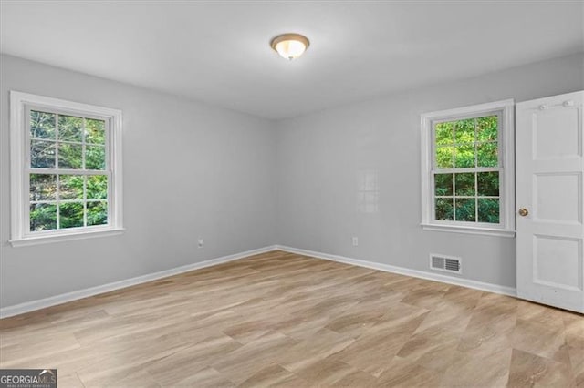 spare room with light wood-style flooring, visible vents, and baseboards